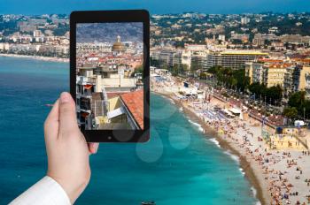 travel concept - tourist taking photo of Nice city on Azure coast, France on mobile gadget