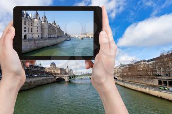 travel concept - tourist taking photo of Conciergerie palace, Pont Neuf, Pont de Notre Dame in Paris in spring on mobile gadget, France