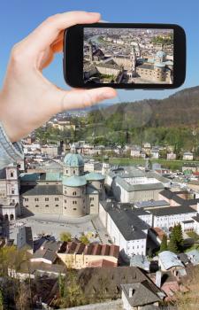 travel concept - tourist taking photo of Salzburg city from the Hohensalzburg Castle on mobile gadget