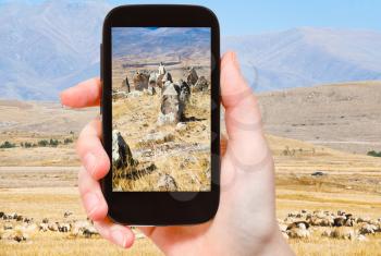 travel concept - tourist takes picture of standing menhirs of Zorats Karer (Carahunge) - pre-history megalithic monument in Armenia on smartphone,