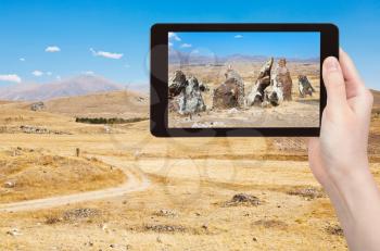 travel concept - tourist takes picture of megalithic standing stone of Zorats Karer (Carahunge) - pre-history monument in Armenia on smartphone,