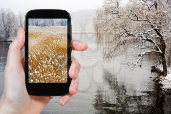 travel concept - tourist takes picture of Hudson river in snowing in winter on smartphone, USA