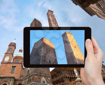 travel concept - tourist takes picture of Due Torri -two tower - symbol of city in Bologna, Italy on tablet pc