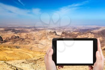 travel concept - tourist photograph mountain landscape of Jordan near Petra on tablet pc with cut out screen with blank place for advertising logo