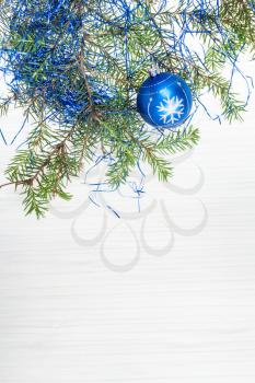 Christmas greeting card - border from one blue Xmas ball and tree branch on blank paper background