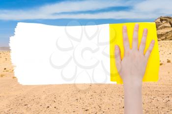 ecology concept - hand deletes sand of desert by yellow rag from image and white empty copy space are appearing