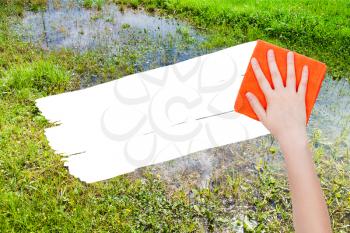 ecology concept - hand deletes swamp by orange rag from image and white empty copy space are appearing