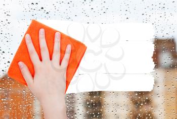 weather concept - hand deletes rain drops on window by orange rag from image and white empty copy space are appearing