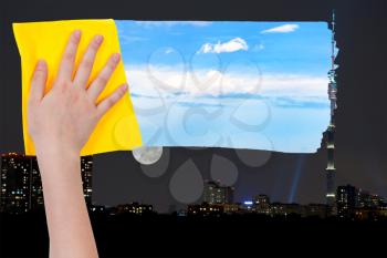 weather concept - hand deletes night over city by yellow cloth from image and day blue sky is appearing