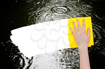 weather concept - hand deletes rainy puddle by yellow rag from image and white empty copy space are appearing