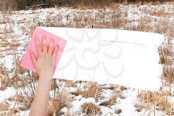 season concept - hand deletes frozen swamp by pink rag from image and white empty copy space are appearing
