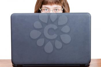 girl with glasses looks over cover of open laptop