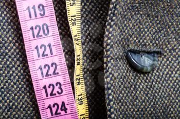tailor measuring tapes and half buttoned button on tweed jacket close up