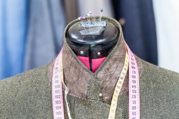 tailoring of male green tweed jacket on mannequin and ready suits on background