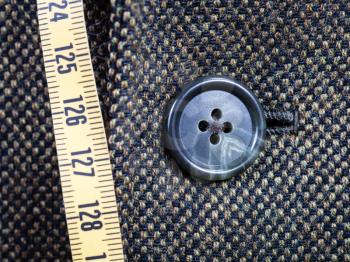tailor measuring tape and buttoned button on tweed jacket close up