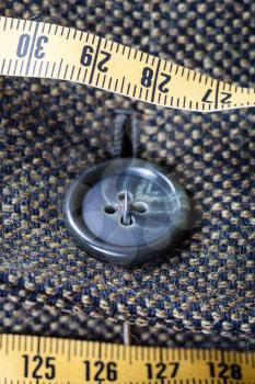 attaching of button to green tweed jacket by needle close up