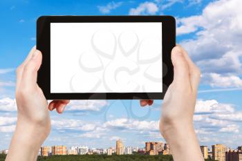 travel concept - hand holds smartphone with cut out screen and blue summer sky over city on background