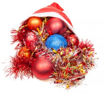 christmas gifts - xmas balls, star and decorations spill out from red santa hat on white background