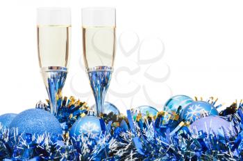 two glasses of sparkling wine at blue Christmas baubles isolated on white background