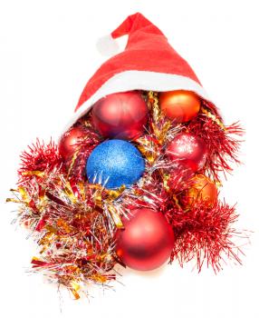 christmas gifts - xmas decorations and tinsel fall out from red santa hat on white background
