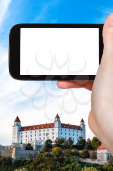 travel concept - tourist photographs of Bratislava Hrad castle on smartphone with cut out screen with blank place for advertising logo