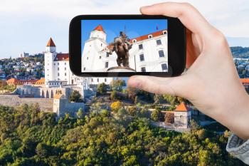 travel concept - tourist photos statue of King Svatopluk I in Bratislava Hrad castle on smartphone