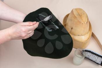 workshop for alpine felt hat making - hatter applies an adhesive a felt hood for shaping on wooden dummy