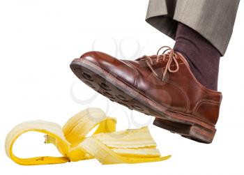 male foot in the left brown shoe slips on a banana peel isolated on white background