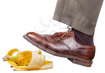 male leg in the left brown shoe slips on a banana peel isolated on white background