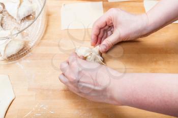 woman prepares dumplings from rolled dough on table