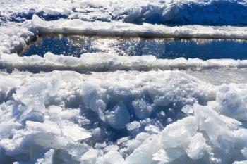 broken ice blocks and ice-hole in frozen river in winter