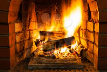 burning firewood in brick fireplace in country cottage