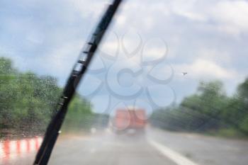 wiping windscreen during driving car on highway in rain (focus on glass)
