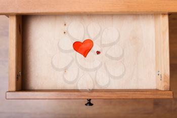top view of little and big red hearts in open drawer of nightstand