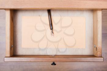 top view of nib pen, paper envelope in open drawer of nightstand