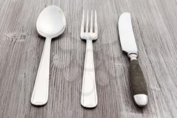 food concept - flatware set from table knife, fork, soup spoon on light brown wooden board