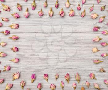 frame from many natural pink rose flower buds on wooden plank