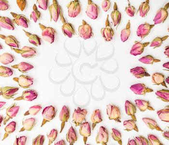 frame from many natural pink rose flower buds close up on white textured paper background