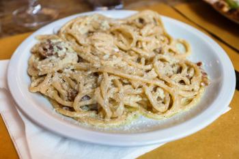 travel to Italy - spaghetti ala carbonara on white plate in Rome
