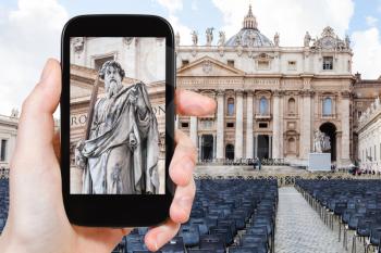 travel concept - tourist photographs Apostle Paul statue in front of St Peter Basilica in Vatican city on smartphone in Italy