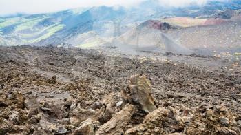 travel to Italy - cloud on frozen lava field on Mount Etna in Sicily in summer day