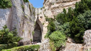 travel to Italy - tourists near Orecchio di Dionisio (Ear of Dionysius) cave in Temenites Hill in latomie del paradiso area of Archaeological Park of Syracuse city in Sicily