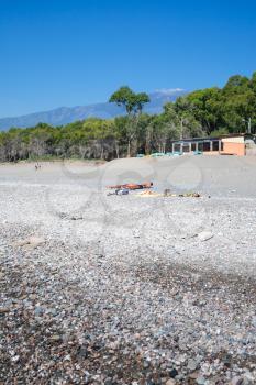 CALATABIANO, ITALY - JUNE 28, 2011: people on beach San Marco on Ionian Sea in Sicily and view of Etna volcano. This is clean, long, calm, small pebbled beach, it is free for most of the extension.