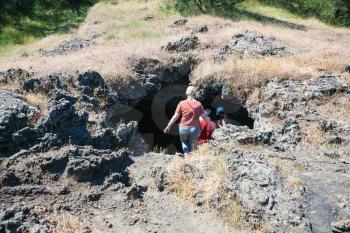 ETNA, ITALY - JULY 1, 2011 - tourists visit a cave in old crater of Etna volcano. Mount Etna is active volcano on the east coast of Sicily, the tallest active volcano in Europe