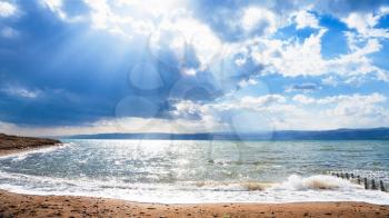 Travel to Middle East country Kingdom of Jordan - sunbeams passes through blue clouds over Dead Sea in winter