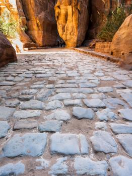 Travel to Middle East country Kingdom of Jordan - stone pavement of Al Siq passage to ancient Petra town in winter