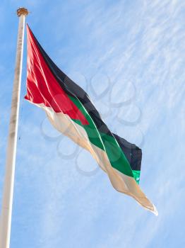 Travel to Middle East country Kingdom of Jordan - Flag of the Arab Revolt outdoors in Aqaba city with blue sky with white clouds in background