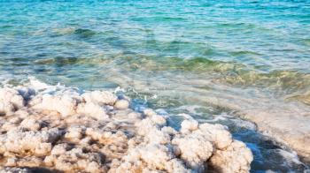 Travel to Middle East country Kingdom of Jordan - salt crystals on shore of Dead Sea in sunny winter day