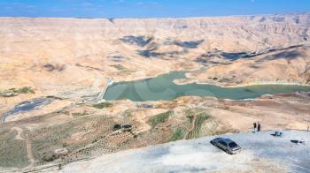 DHIBAN, JORDAN - FEBRUARY 20, 2012: people at viewpoint over Al Mujib dam on Wadi Mujib river on King's highway in winter. King's Road was trade route on ancient Near East from Egypt to Aqaba