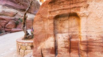PETRA, JORDAN - FEBRUARY 21, 2012: tourists near stone relief in Al Siq pass to ancient Petra town in winter. Rock-cut town Petra was established about 312 BC as the capital city of the Arab Nabataean